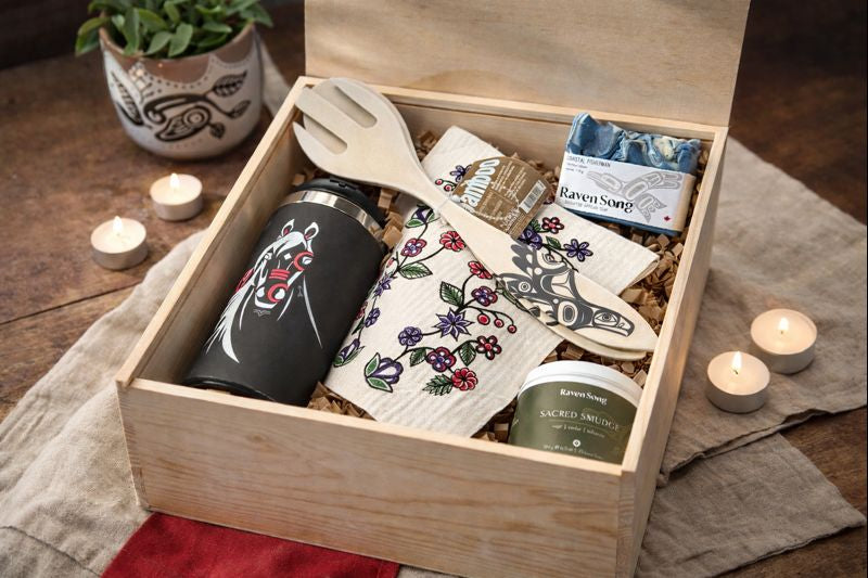 curated wooden gift box containing Indigenous design items, candle, eco cloth, serving spoon, candle and soap with decorative pieces around