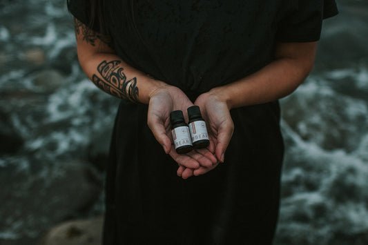 Person holding three small bottles in their hands with a blurred natural background