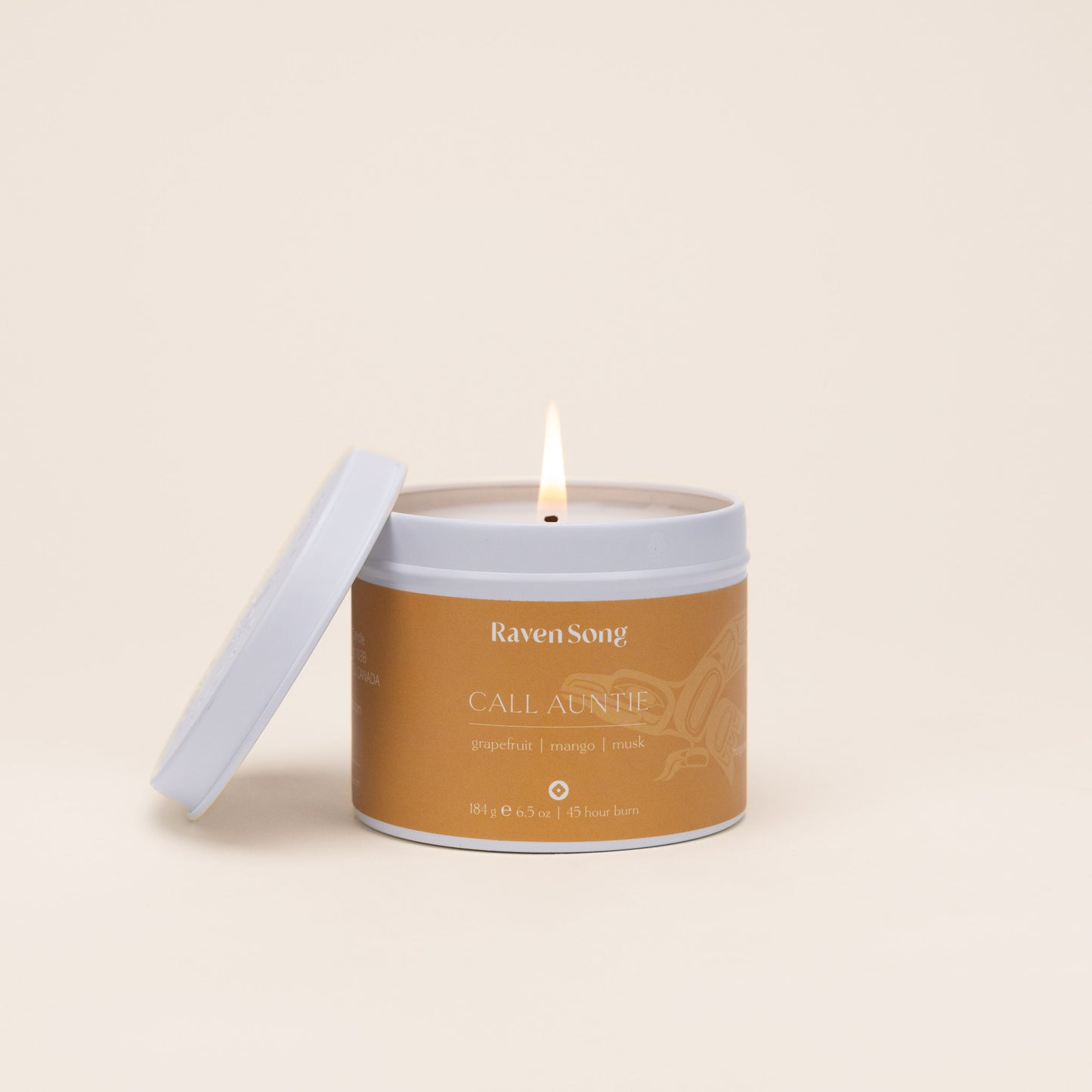 Candle in a jar labeled 'Raven Song' with burning wick