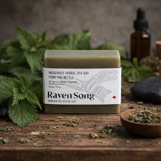 Handcrafted artisan soap bar with 'Raven Song' branding on a wooden surface with herbs and a bottle in the background.