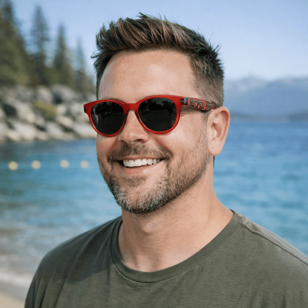 Man wearing Eagle Vision sunglasses by Haida artist Allan Weir, standing on a beach next to the water