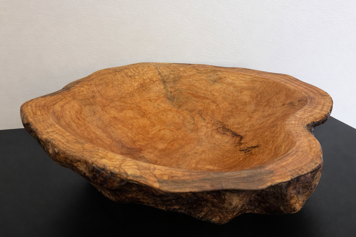 Wooden bowl with natural edge on a black surface