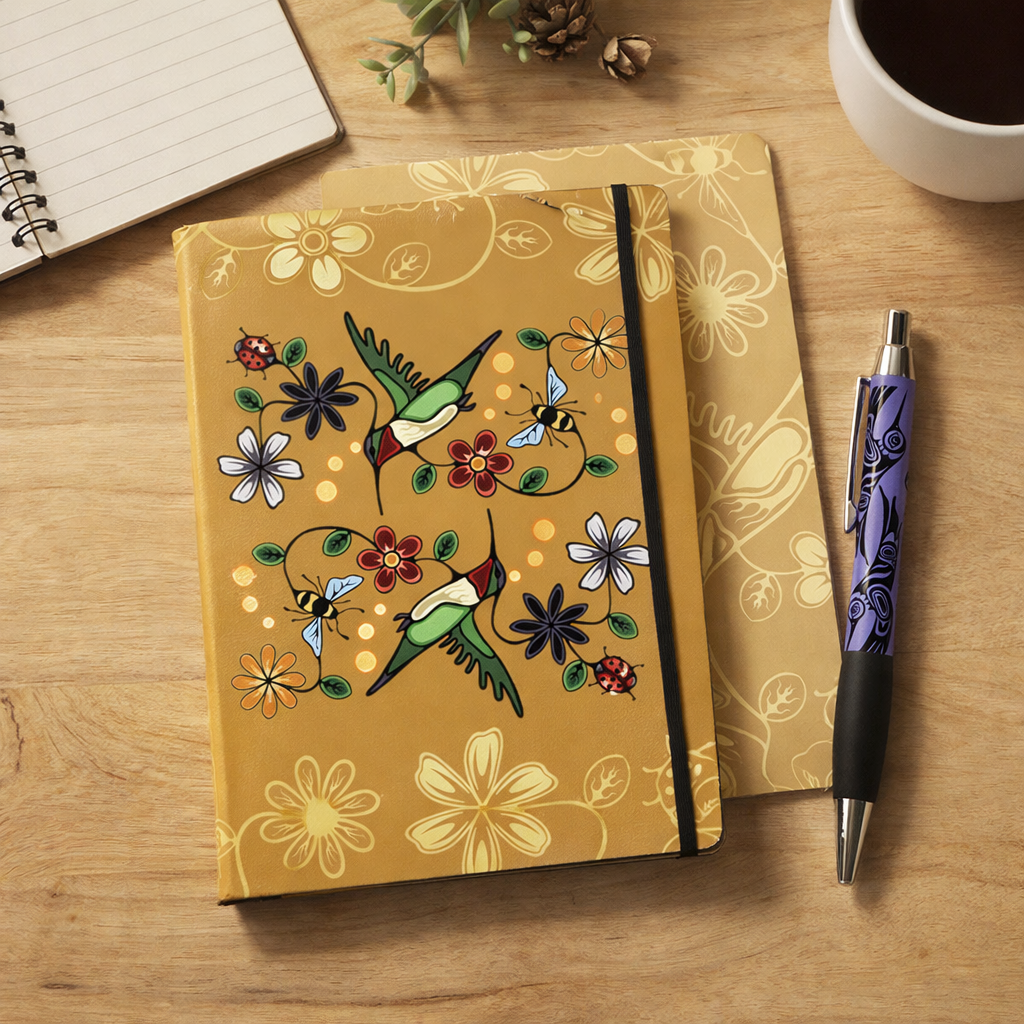 Indigenous design hummingbird and florals notebook on a wooden surface with a pen and coffee.