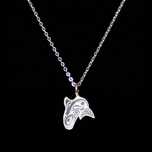 Silver Indigenous whale design-shaped pendant on a chain against a black background