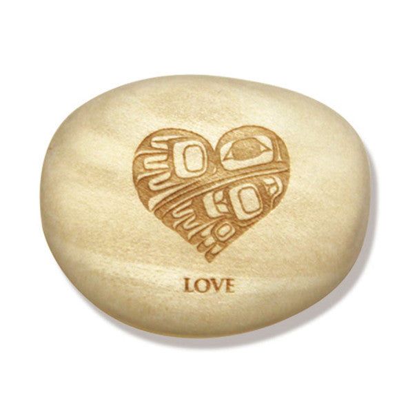 Photo of Indigenous Artwork by Gordon White of a heart carved into a wood pebble with the word "LOVE" engraved at the bottom. The pebble / stone is displayed in front of a white background