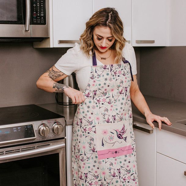 Woman in a kitchen wearing a floral apron.