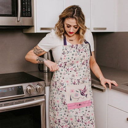 Woman in a kitchen wearing a floral apron.