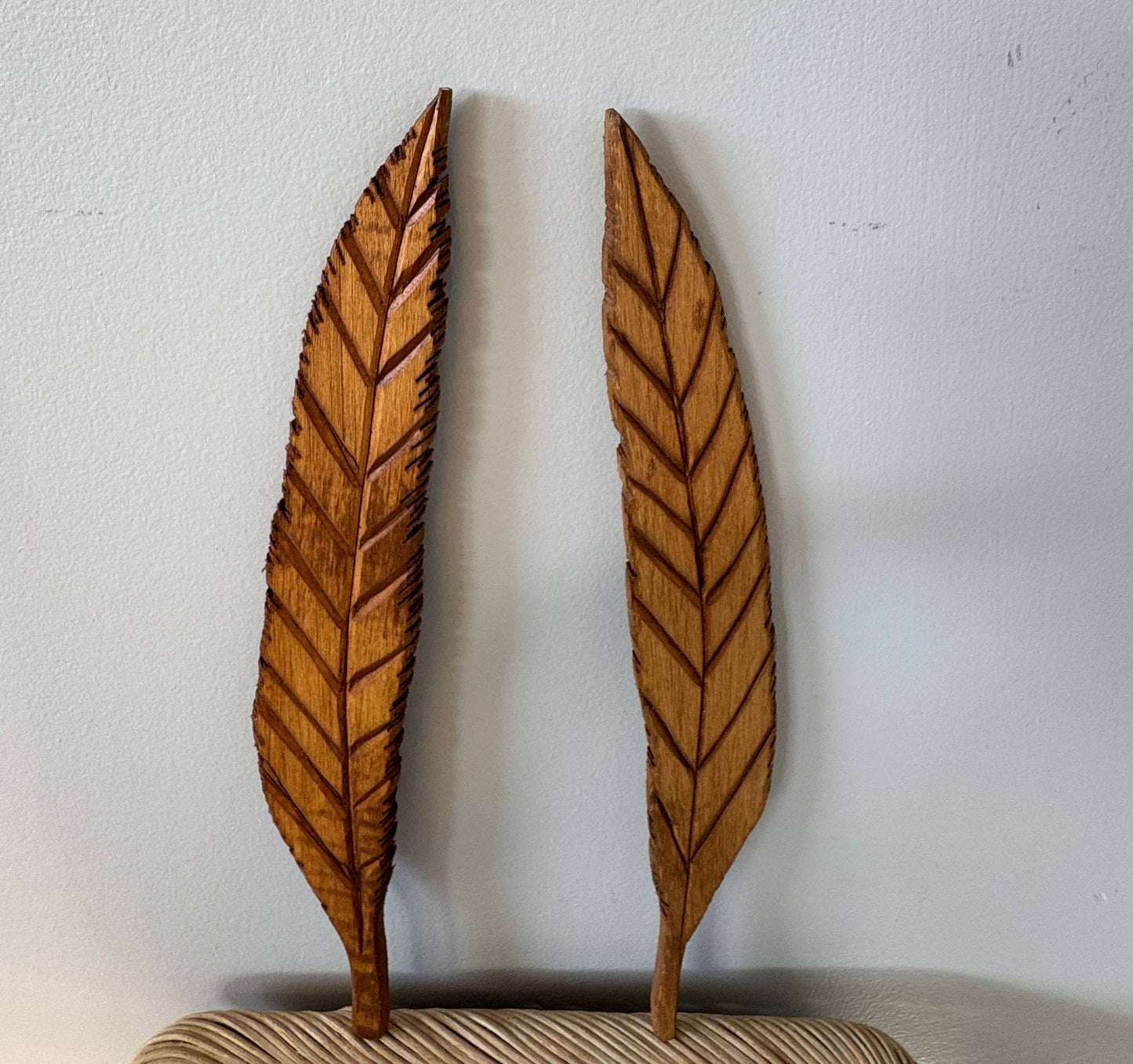 Two wooden feather-shaped decorations