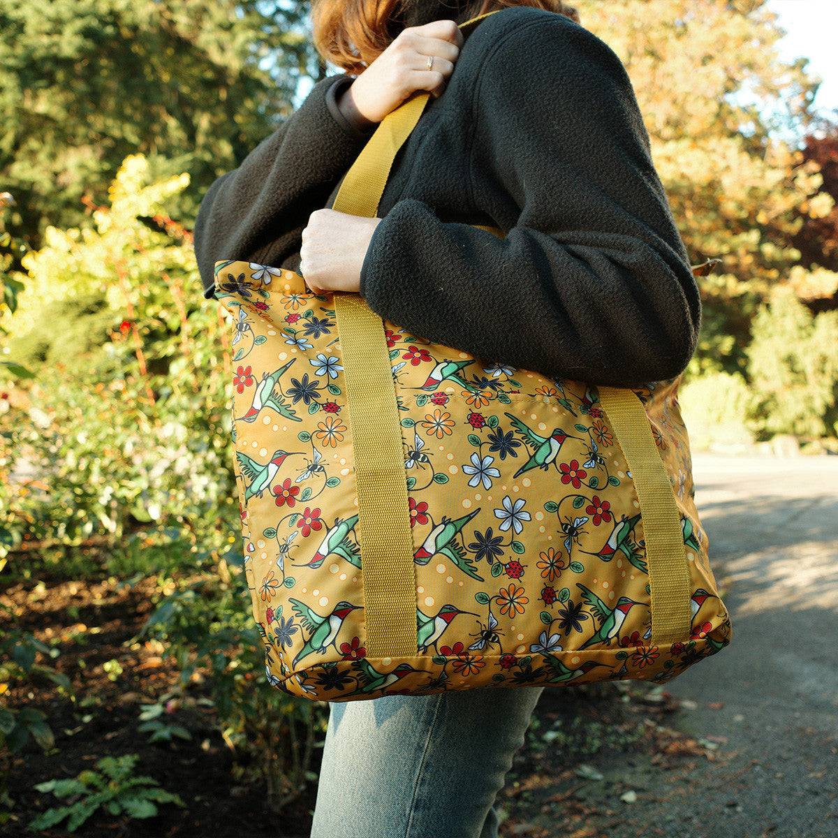 Person carrying a yellow floral-patterned bag outdoors