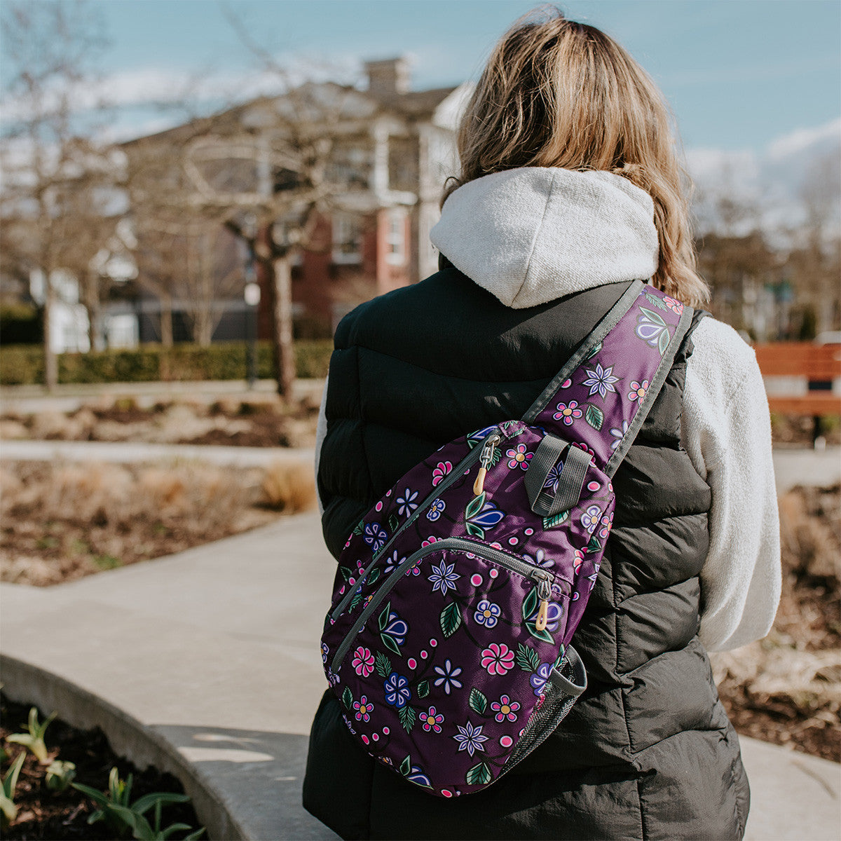 Person wearing the Ojibwe Florals sling pack across their back on a city sidewalk
