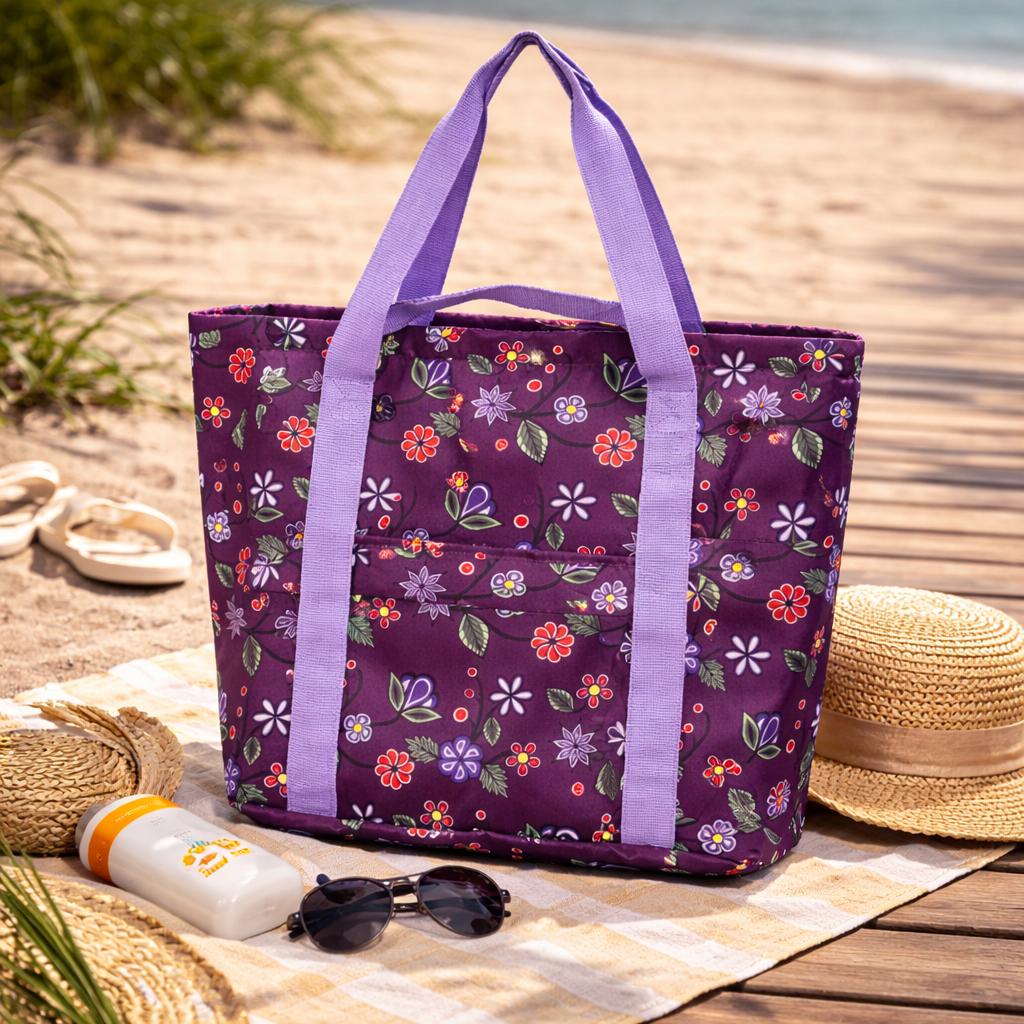 Purple floral tote bag on a beach with a straw hat, sunglasses, and sunscreen.