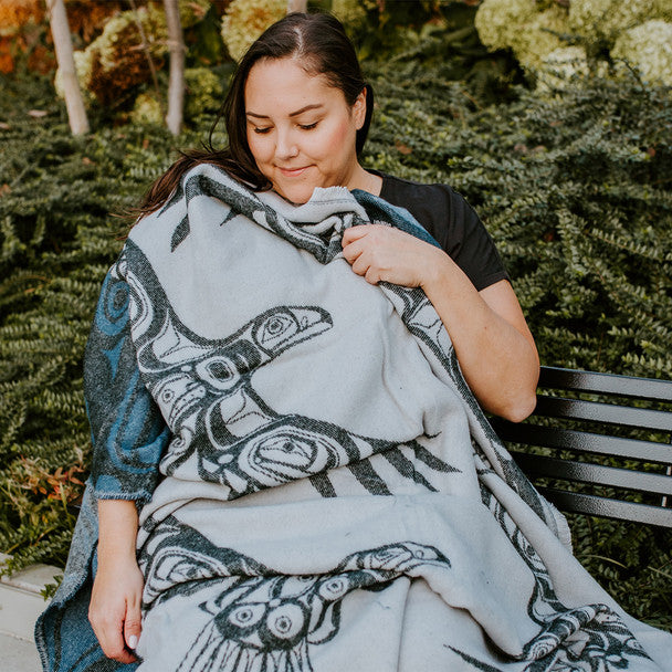 Women sitting on a bench with the Soaring Eagle woven blanket draped over her
