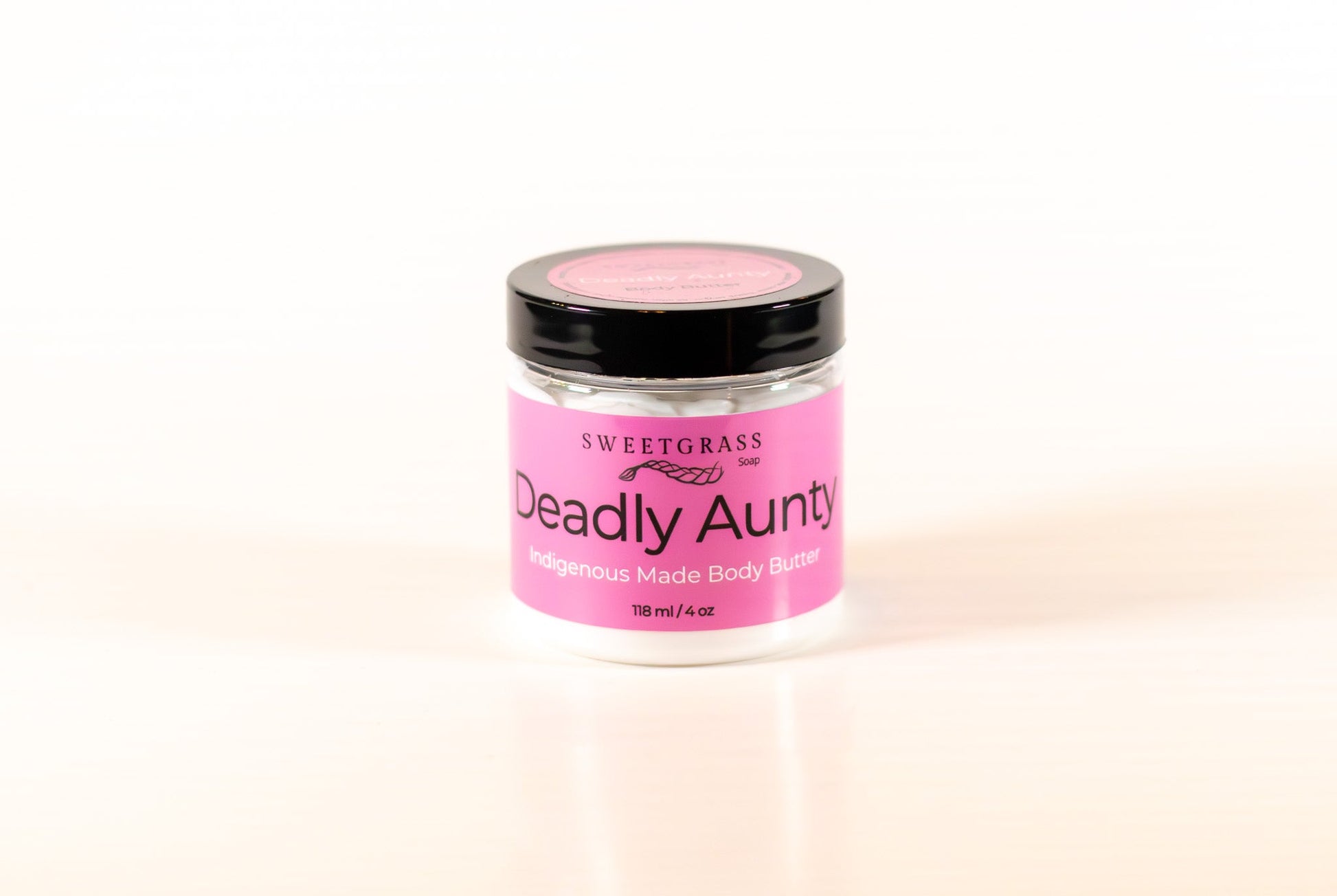 Sweetgrass Soap Deadly Aunty body butter in a clear jar with a black lid and pink label, 118 ml.