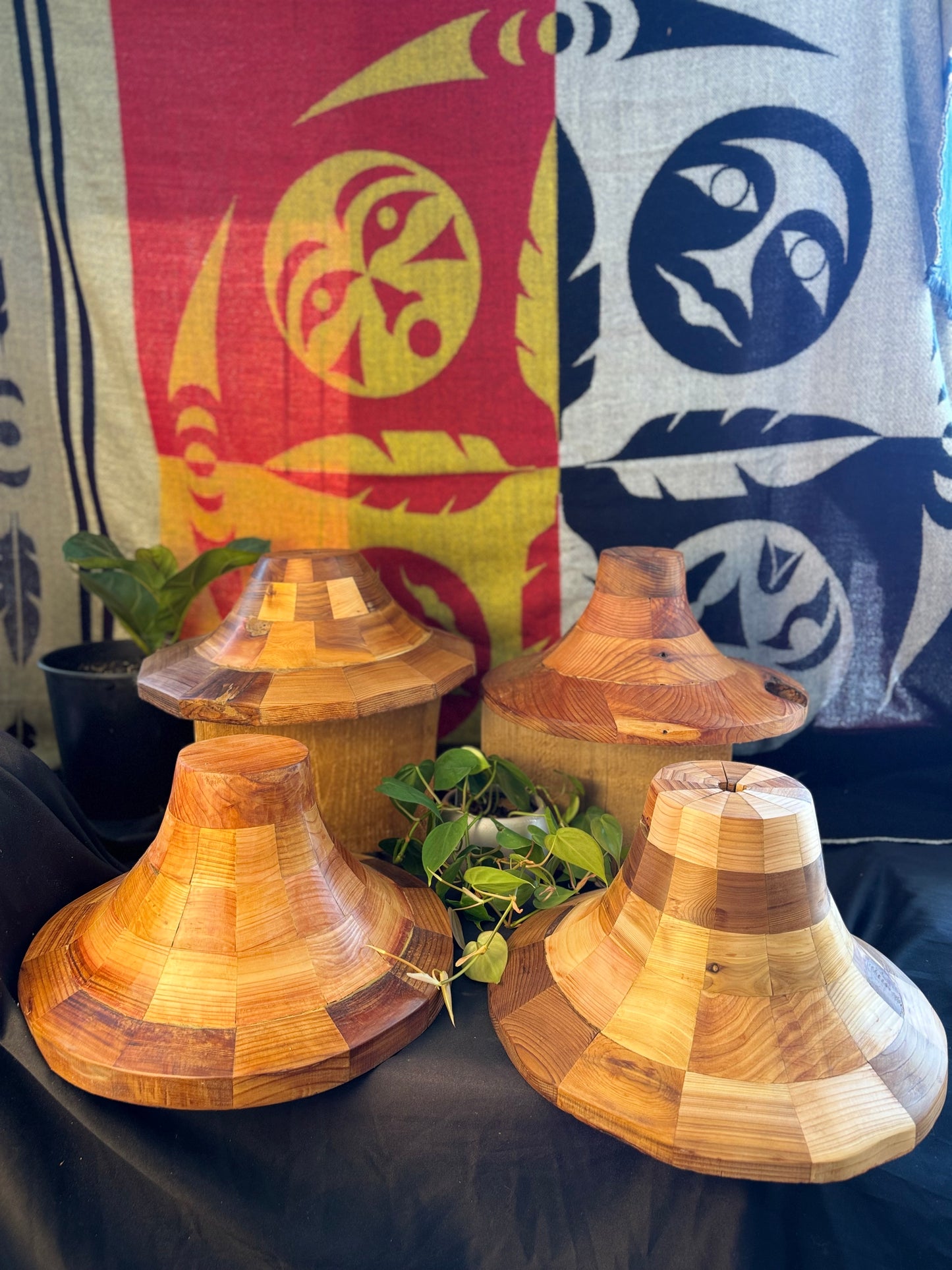 4 cedar hat forms displayed together in front of an Indigenous blanket