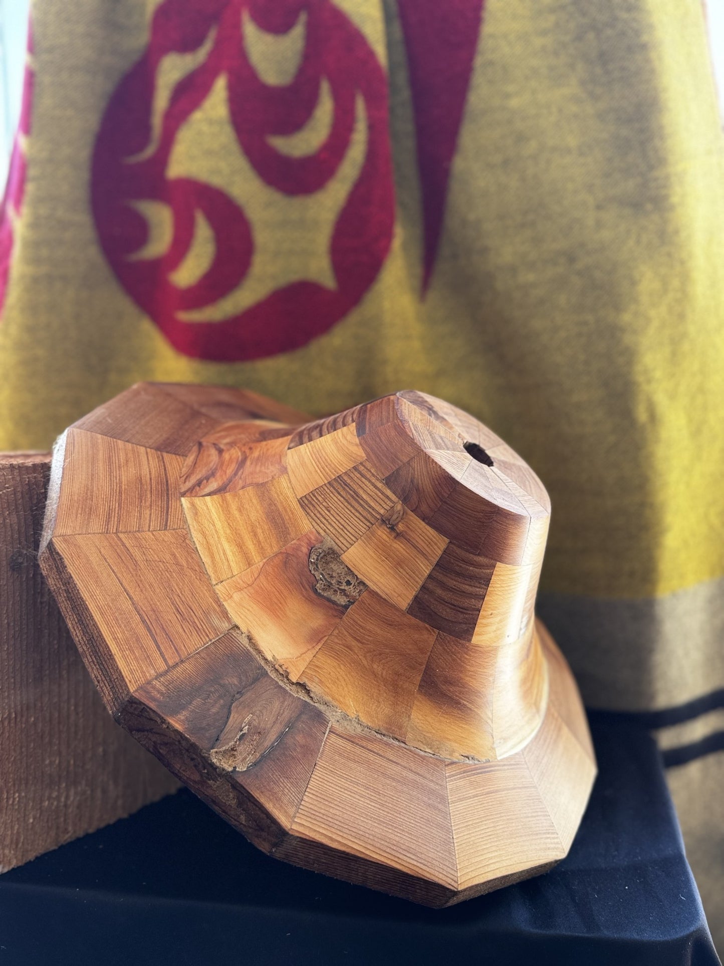 Angled view of the cedar hat form on a wood stand