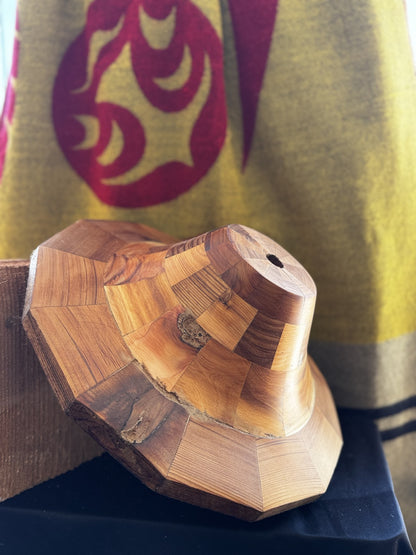Angled view of the cedar hat form on a wood stand