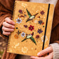 Spiral journal with hummingbird and floral design held in hands