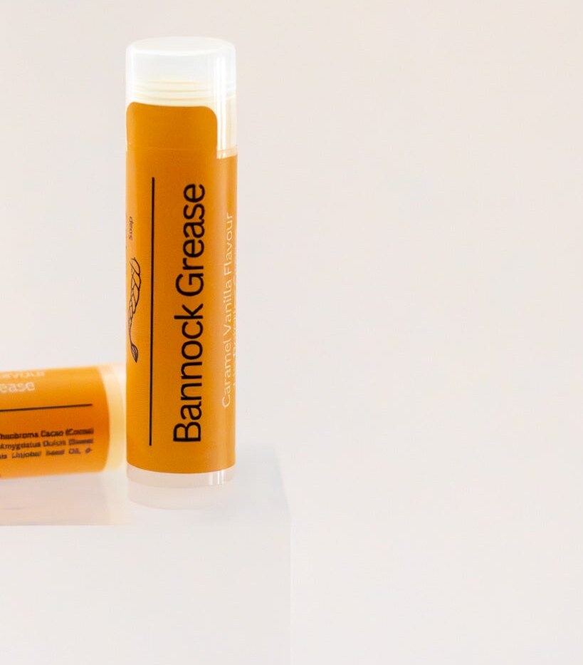 Bannock Grease lip balm tube standing upright, orange label, caramel vanilla flavour.