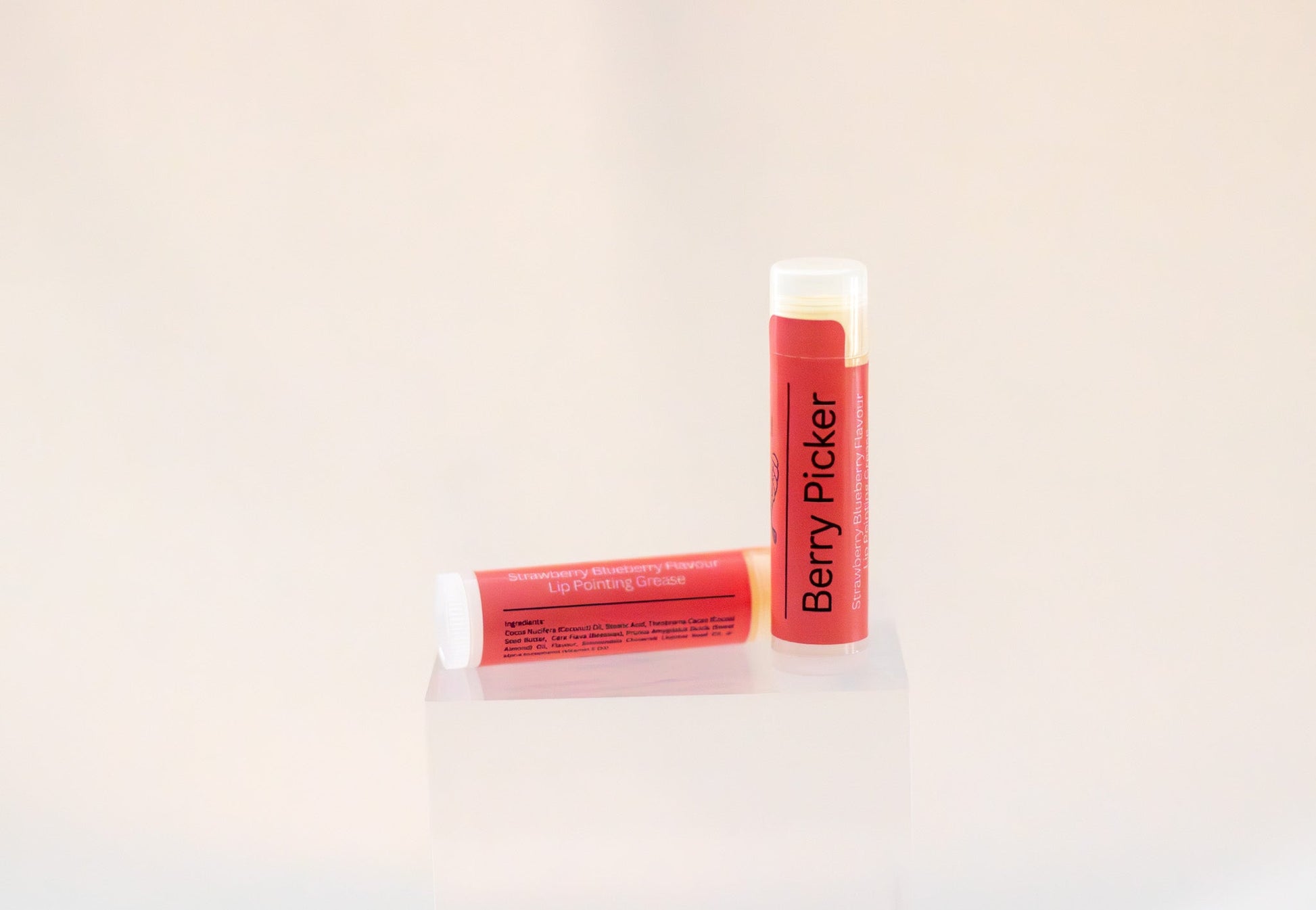 Sweetgrass Soap Berry Picker lip balm twist-up tube with a coral label, two shown.