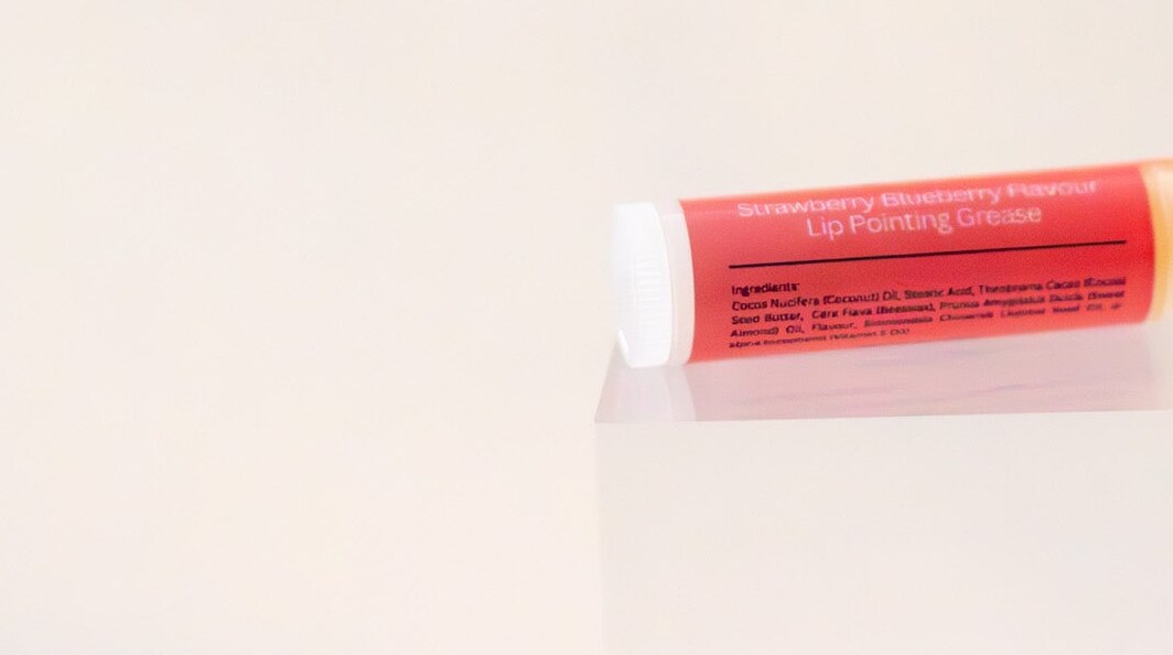 Berry Picker lip balm tube on its side showing the ingredient panel.