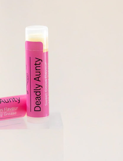 Deadly Aunty lip balm tube standing upright, pink label, sweet citrus flavour.
