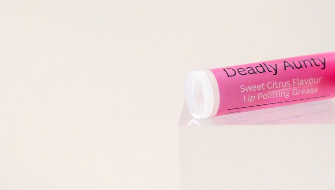 Deadly Aunty lip balm tube on its side showing the ingredient panel.