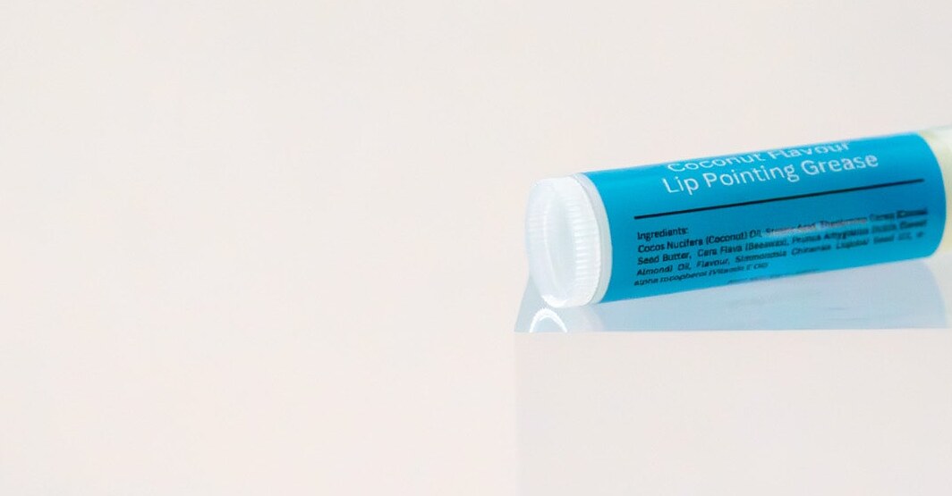 Deadly Uncle lip balm tube on its side showing the ingredient panel.