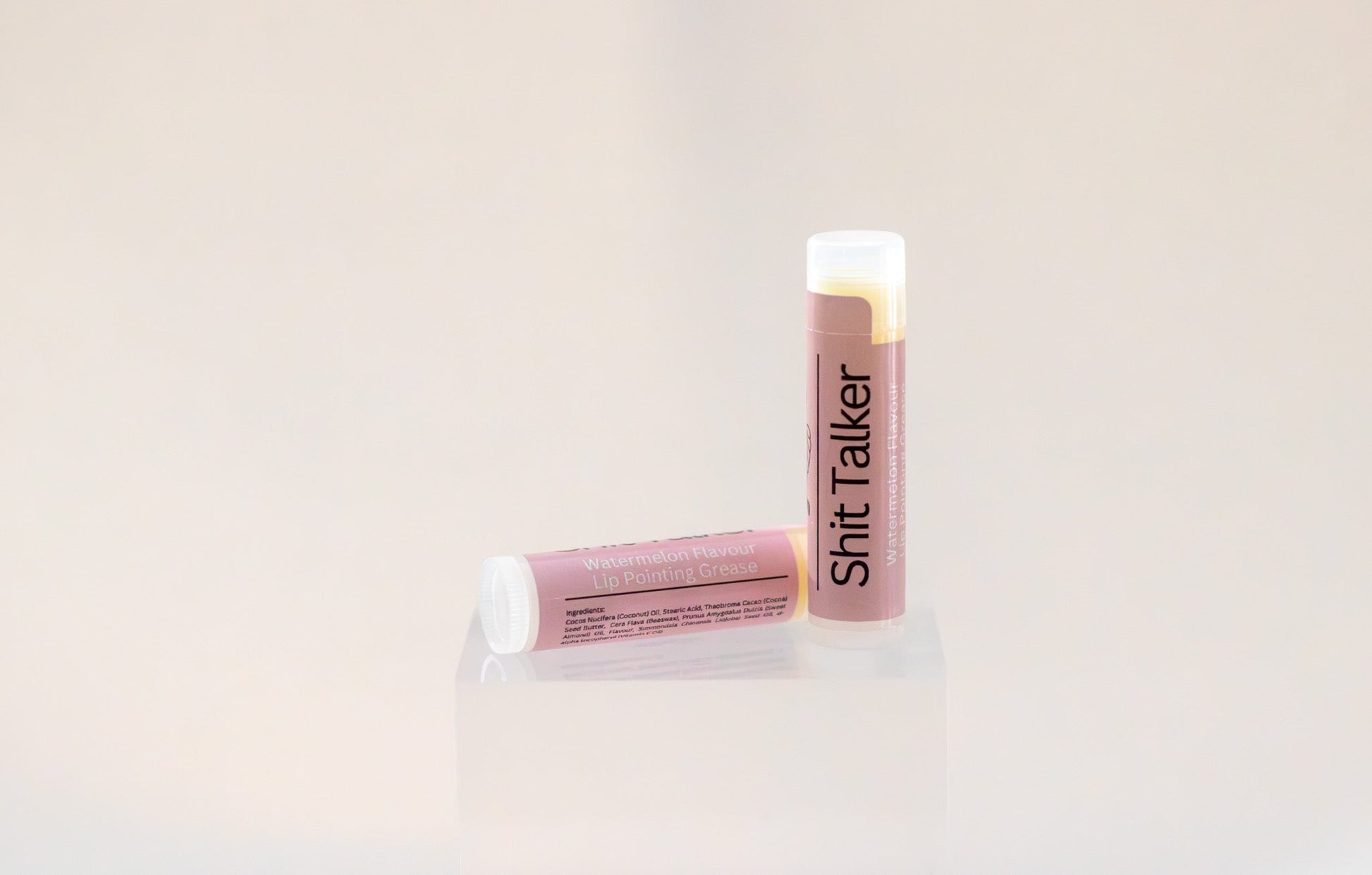 Sweetgrass Soap Sh*t Talker lip balm twist-up tube with a dusty pink watermelon label, two shown.
