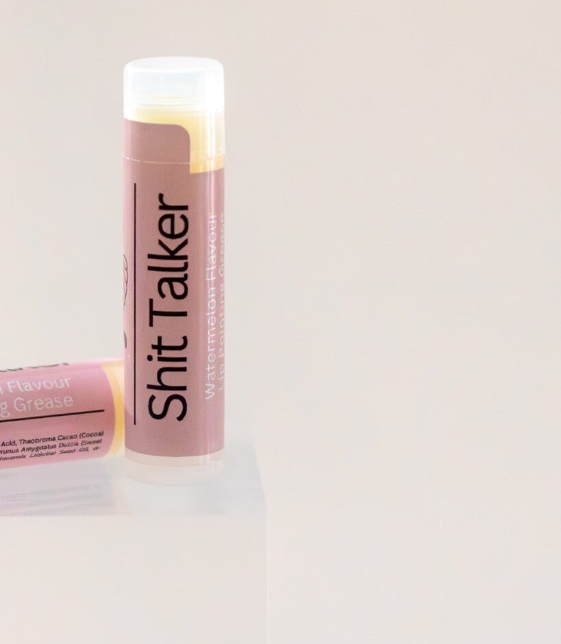 Sh*t Talker lip balm tube standing upright, dusty pink label, watermelon flavour.