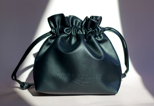 Sweetgrass Soap black vegan-leather drawstring toiletry bag with an embossed logo.