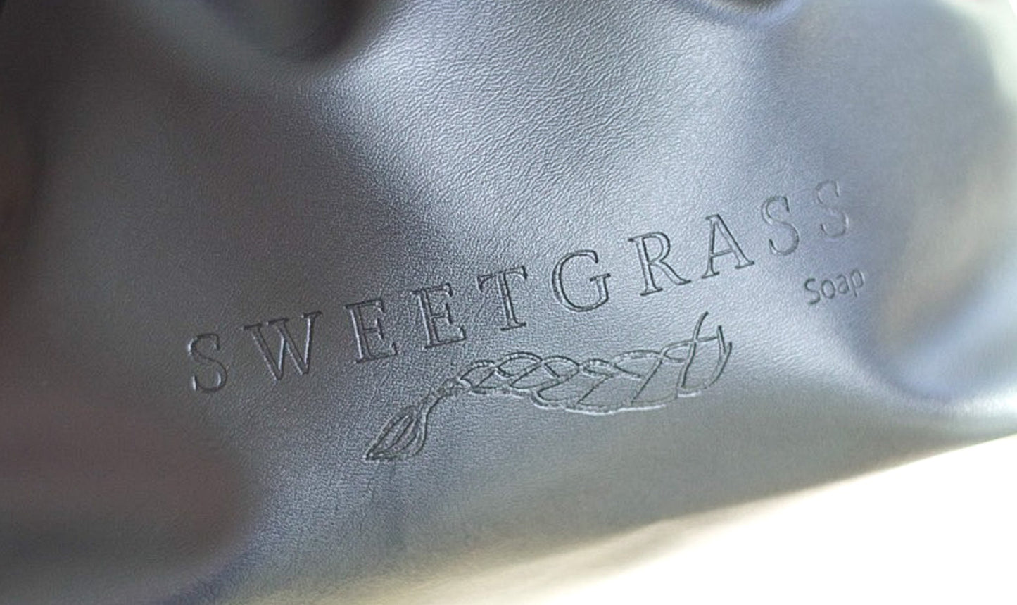 Detail of the soft vegan-leather finish and embossed logo on the toiletry bag.