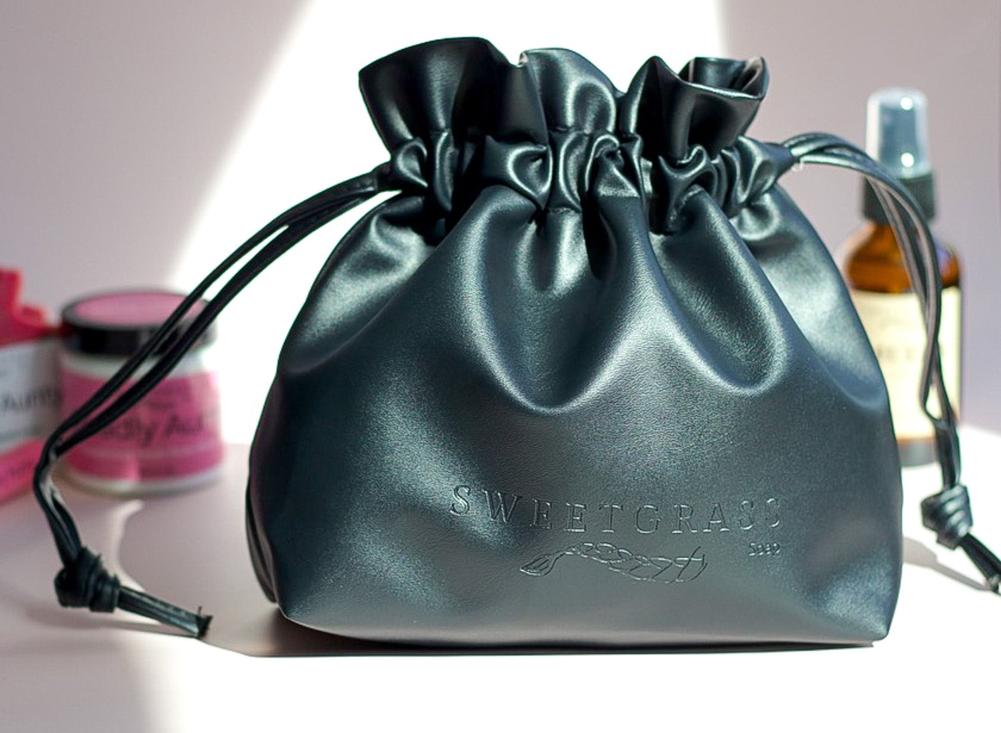 Black drawstring toiletry bag styled with Sweetgrass Soap body butter and smudge spray.
