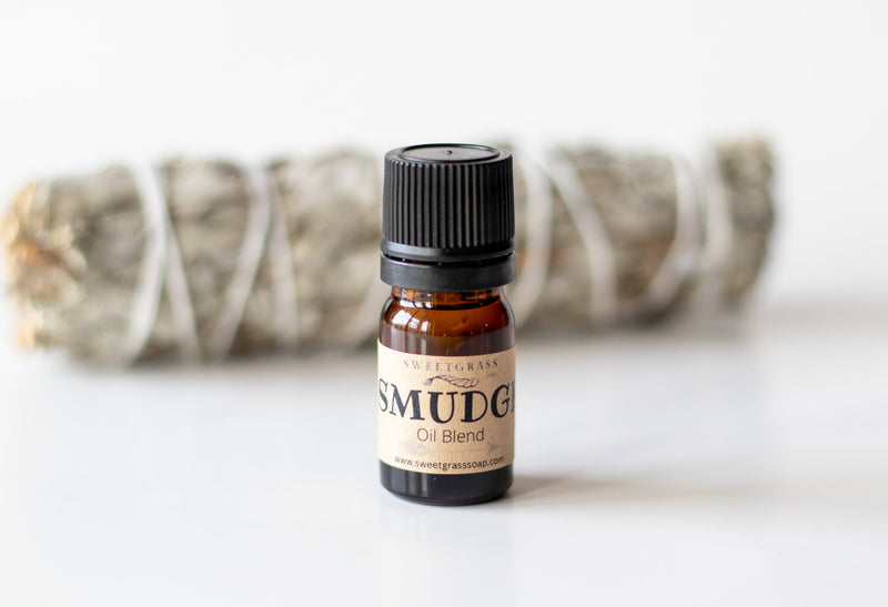Sweetgrass Soap Smudge Oil Blend in a small 5 ml amber bottle with a black cap and kraft label, a sage bundle behind.
