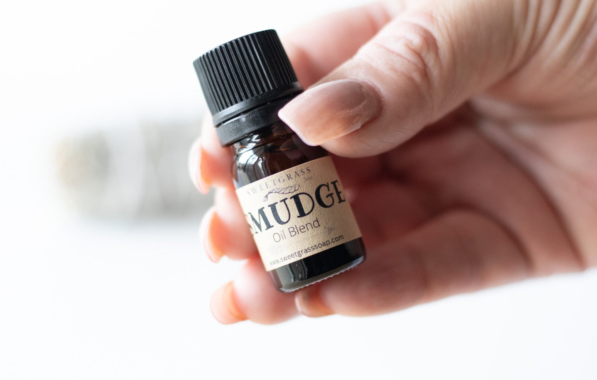 Hand holding the small amber Sweetgrass Soap Smudge Oil Blend bottle.