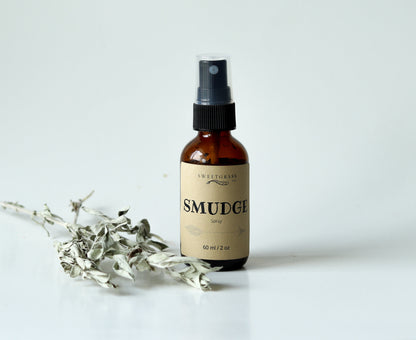 Sweetgrass Soap Smudge Spray in a 2 oz amber glass bottle with a black mister and kraft label, dried sage beside it.