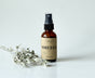 Sweetgrass Soap Smudge Spray in a 2 oz amber glass bottle with a black mister and kraft label, dried sage beside it.