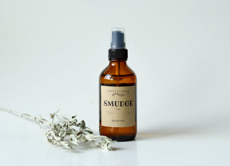 Sweetgrass Soap Smudge Spray in a 4 oz amber glass bottle with a black mister and kraft label, dried sage beside it.