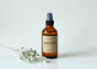 Sweetgrass Soap Smudge Spray in a 4 oz amber glass bottle with a black mister and kraft label, dried sage beside it.