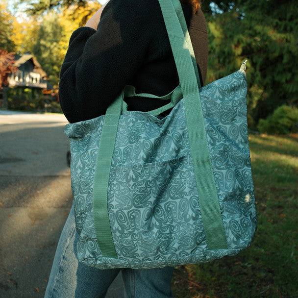 Person holding a green and white patterned tote bag outdoors