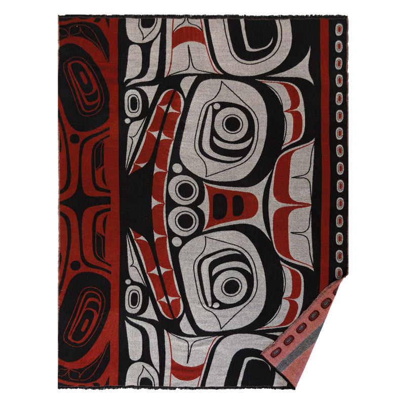 Decorative blanket with Indigenous design featuring red, black, and gray patterns.