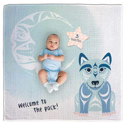Baby in a blue onesie lying on a blanket with a wolf design and 'Welcome to the pack!' text.